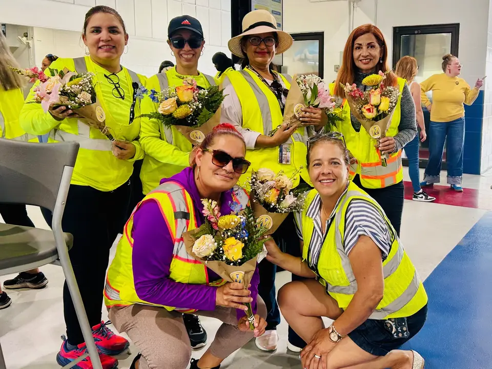 Team members holding hand-tied bouquets at a workplace appreciation event