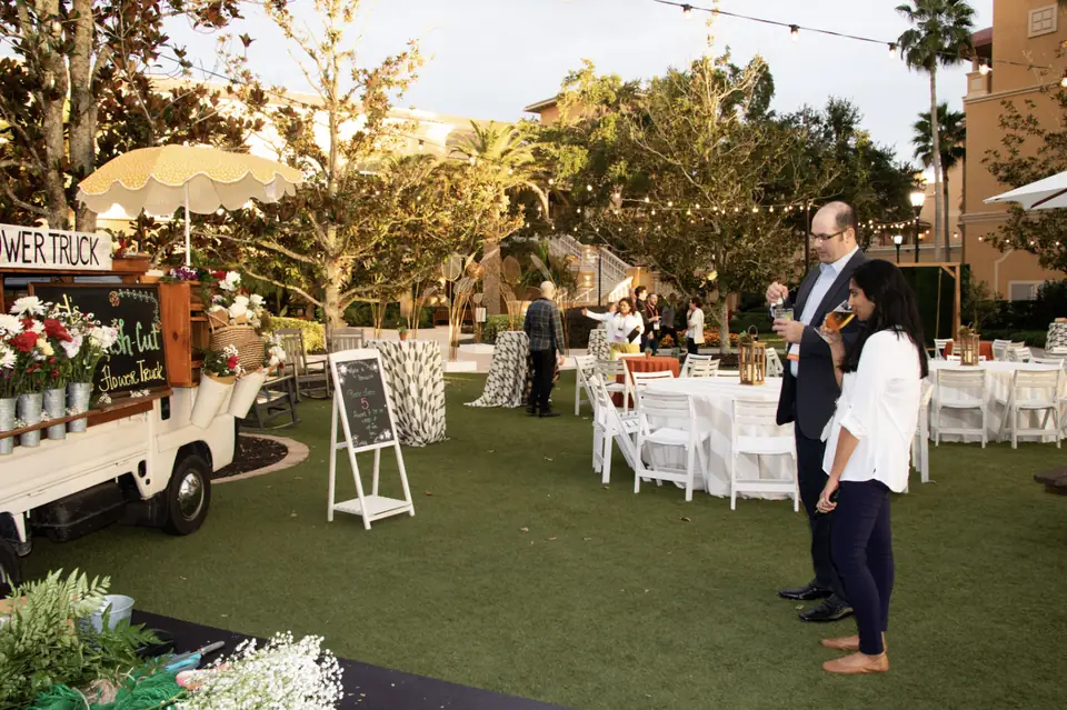 The flower truck set up on an event lawn beside lounge seating and string lights